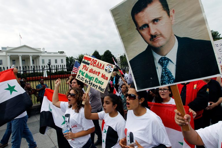 Syrian demonstrators  carry an image of Syrian President Bashar Assad during a protest against US military action in Syria, Monday, Sept. 9, 2013, in front of the White House in Washington. (AP Photo/Jose Luis Magana)