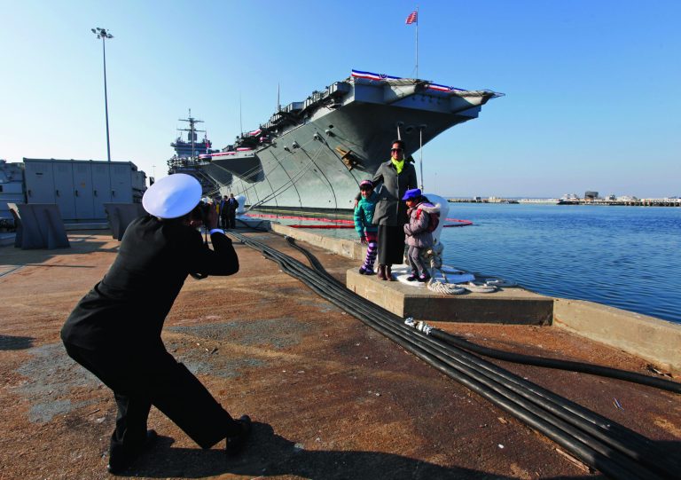 Senior Chief Nageer Rahim, originally from Guyane, photographs his wife, Aliya and their kids in front of the USS Enterprise after an inactivation ceremony for the first nuclear powered aircraft carrier USS Enterprise at Naval Station Norfolk Saturday, Dec. 1, 2012 in Norfolk, VA. The ship served in the fleet for 51 years. (AP Photo/Steve Helber)