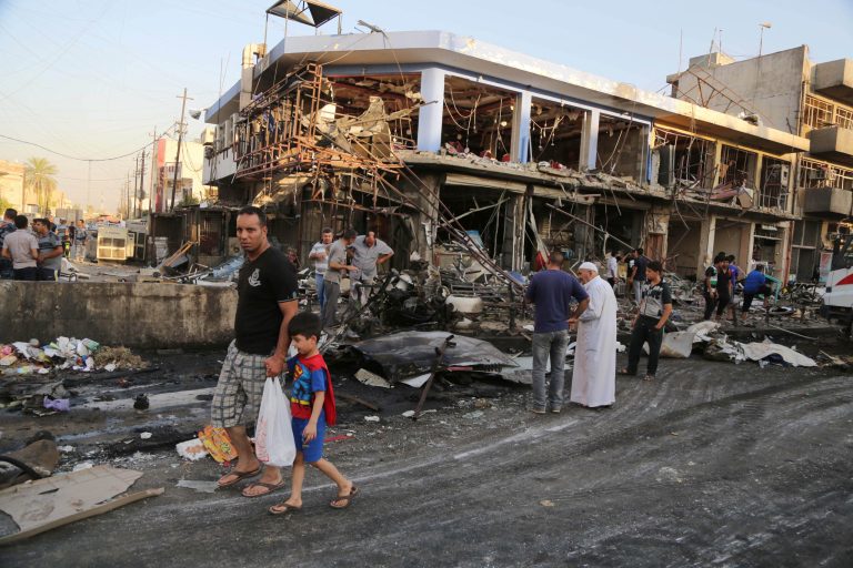 Civilians inspect the site of a car bomb attack near a restaurant in the southeastern district of New Baghdad, Iraq, Wednesday, Aug. 13, 2014. A string of attacks in and around the capital killed more than a dozen and wounded dozens. (AP Photo/Karim Kadim)