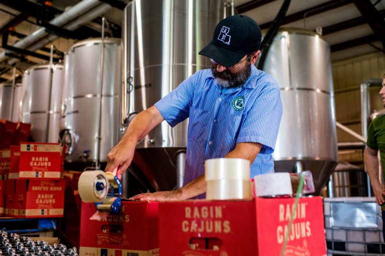 Karlos Knott, president of Bayou Teche Brewing in Arnaudville, La., seals a case of Ragin' Cajuns beer. The beer was created in partnership with the University of Louisiana at Lafayette and is served bottled, in bars, and at UL-Lafayette home football games. (Paul Kieu/The Daily Advertiser via AP)