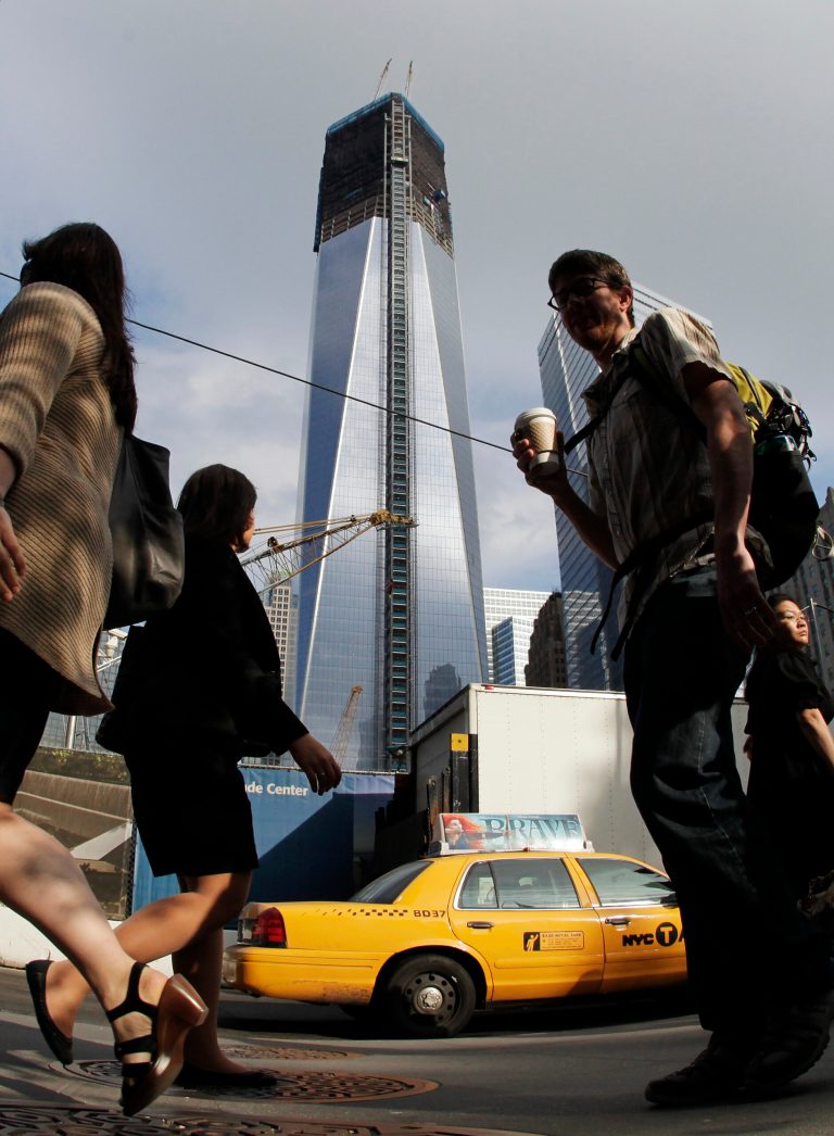   Commuters walk past the World Trade Center construction site and One World Trade Center, center, Thursday, June 14, 2012 in New York. President Barack Obama is scheduled to visit the site later Thursday. World Trade Center PATH service will be suspended during Obama's visit and PATH trains from Newark will terminate at Grove Street in Jersey City.(AP Photo/Mark Lennihan)  