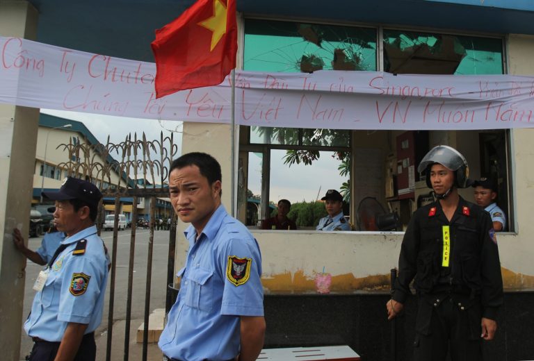 Security staff guard the entrance to a Singaporean factory in an industrial park in Binh Duong province, Vietnam Saturday, May 17, 2014, after mobs attacked foreign owned factories following anti-China protests. Vietnam's prime minister ordered an end Saturday to all 