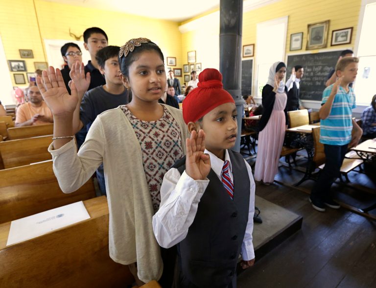 Bikramjit Singh, nine, center, and his sister Parneet Kaur, 11, immigrants from India, joined more than a dozen other young people who took an oath of citizenship, Thursday, July 2, 2015, in Sacramento, Calif. (AP Photo)Â 