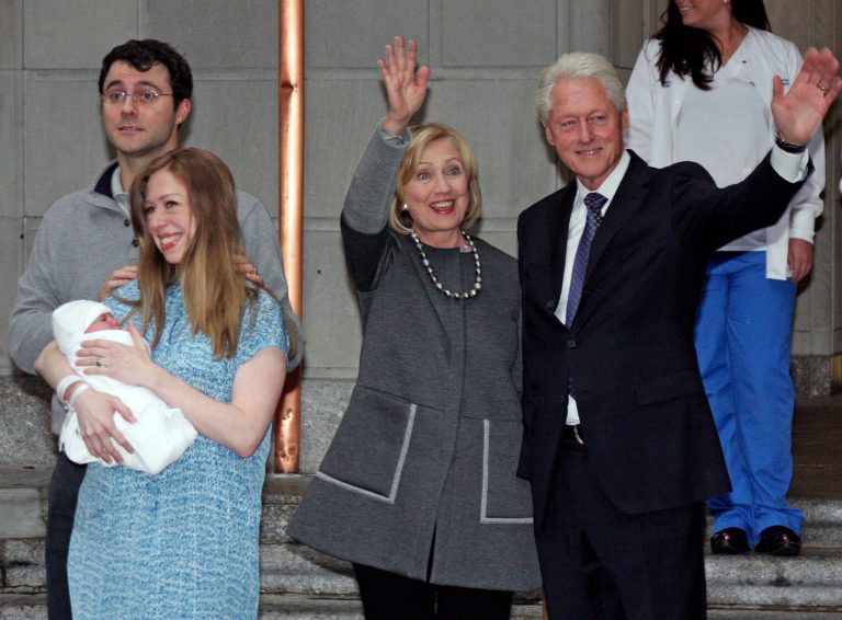Former President Bill Clinton and former Secretary of State Hillary Clinton wave to the media as Marc Mezvinsky and Chelsea Clinton pose for photographers with their newborn baby, Charlotte, in New York on Sept. 29, 2014. (AP Photo/William Regan)