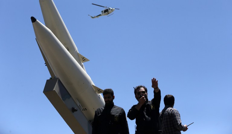 A member of Iranian Revolutionary Guard speaks on his walkie talkie while Zolfaghar surface-to-surface ballistic missiles are displayed in an annual pro-Palestinian rally marking Al-Quds (Jerusalem) Day in Tehran, Iran, Friday, June 23, 2017. (AP Photo/Vahid Salemi)