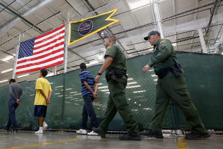 FILE - This June 18, 2014, file photo shows young detainees being escorted to an area to make phone calls as hundreds of mostly Central American immigrant children are being processed and held at the U.S. Customs and Border Protection Nogales Placement Center in Nogales, Ariz. Thousands of immigrant children crossing alone into the U.S. can live in American cities, attend public schools and possibly work here for years without consequences. The chief reasons are an overburdened, deeply flawed system of immigration courts and a 2002 law intended to protect children's welfare, an Associated Press investigation finds.  (AP Photo/Ross D. Franklin, Pool)