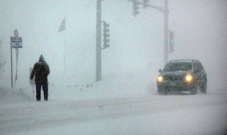 A man waits at a bus stop on Randall Road near Batavia, Ill., Monday, Feb. 17, 2014. The National Weather Service on Monday forecast up to 8 inches of snow for areas of northern Illinois and 5 inches in central Illinois. (AP Photo/Daily Herald, John Starks)