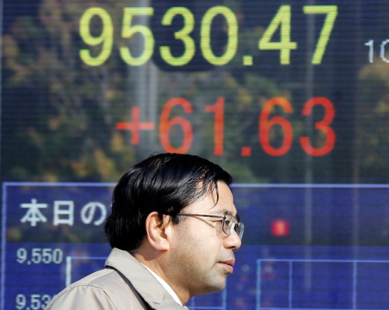   A man walks by an electronic stock board of a securities firm in Tokyo, Thursday, Dec. 6, 2012. Asian stock markets remained in a holding pattern Thursday as investors assessed President Barack Obama's comments that reaching a budget deal to prevent the U.S. from a possible recession was 