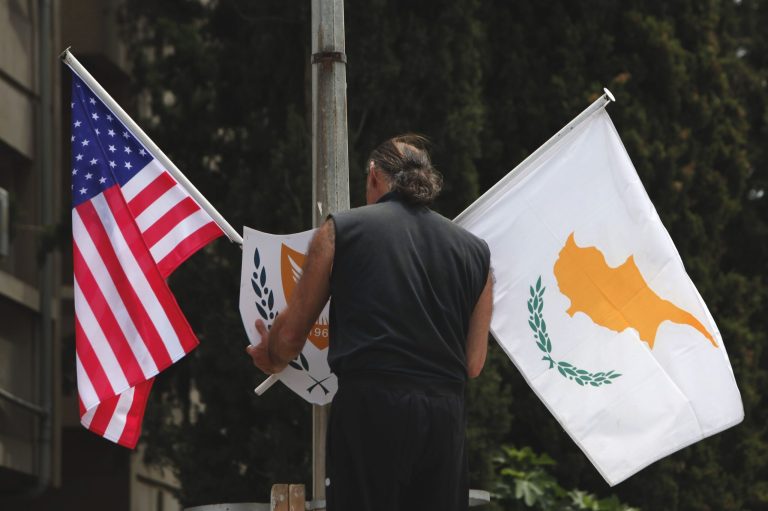A municipality worker places a US flag, left  and Cypriot flag,  on an electricity column, on a street in divided capital Nicosia, Cyprus, Tuesday, May 20, 2014. US Vice President Joe Biden arrives in Cyprus Wednesday for an official, three-day visit to the ethnically divided island. Energy prospects in the east Mediterranean, the situation in Ukraine and talks to reunify Cyprus will top Biden's agenda, who is the most senior American official to visit the island in 52 years. (AP Photo/Petros Karadjias)