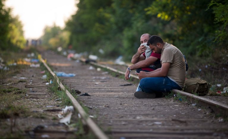 Two men sit on the railway track before crossing the border from Serbia into Hungary, in Roszke, Hungary, Tuesday, Sept. 1, 2015. Migrants fearful of death at sea in overcrowded and flimsy boats have increasingly turned to using a land route towards Europe through the Western Balkans. (AP Photo/Darko Bandic)