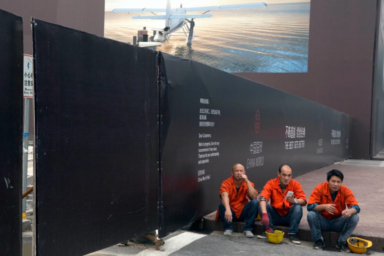 Workers take a break near a billboard depicting a scenic holiday getaway in Beijing Thursday, Oct. 9, 2014. Enthusiasm for free markets runs higher in communist China and Vietnam than in traditional capitalist bastions the United States and United Kingdom, the Pew Research Center reports. (AP Photo/Ng Han Guan)