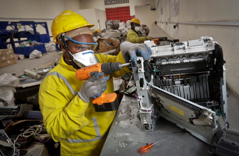 In this photo taken Monday, Aug. 18, 2014, a worker uses an electric screwdriver to dismantle a printer for recycling, at the East African Compliant Recycling facility in Machakos, near Nairobi, in Kenya. The amount of electronic waste generated globally last year is enough to fill 100 Empire State Buildings and represents more than 15 pounds (6.8 kilograms) for every living person, according to the U.N. Environmental Program, with much of that e-waste exported to developing countries like India and Kenya in the form of used goods. (AP Photo/Ben Curtis)