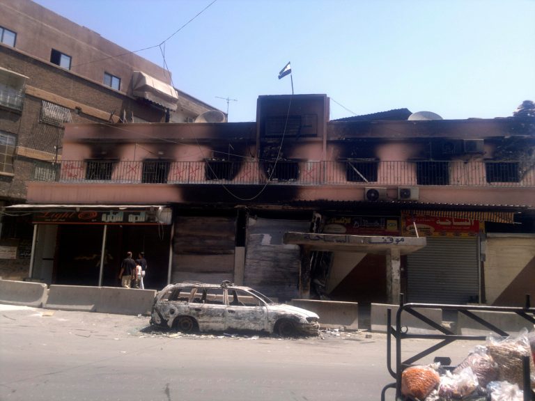 This citizen journalist image shows the Syrian revolutionary flag flying over a gutted police station after fighting between rebels and Syrian troops in the Yarmouk camp for Palestinian refugees in south Damascus, Syria, Saturday, July 21, 2012. This week, fierce fighting between troops and rebels reached the Syrian capital, the central bastion of Bashar Assad's rule, shattering parts of the city and sending thousands of people fleeing to neighboring Lebanon and Iraq. Activists and residents reported a tense calm in Damascus Saturday but said sporadic gunfire and explosions could be heard throughout the night. (AP Photo)
