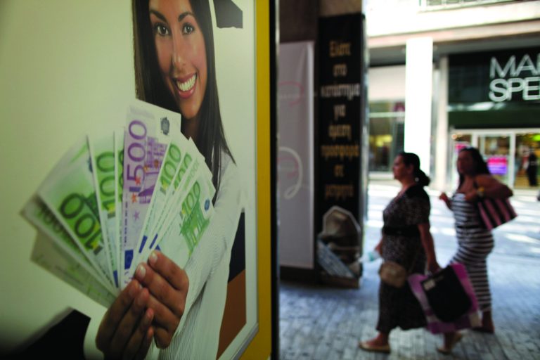 Pedestrians walk outside a pawn shop offering money for gold, in Athens, on Monday, Aug. 20, 2012. Greece's finance officials are seeking to finalize euro 11.5 billion in spending cuts necessary for it to continue receiving the international funding that is protecting it from bankruptcy. (AP Photo/Petros Giannakouris)