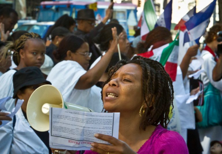 Carla Garcia, center, speaks into a bullhorn during a rally and march of Latin American immigrants, including African descendants from Honduras known as Garifuna, outside the U.S. Citizenship and Immigration Services office on Thursday Aug. 28, 2014 in New York. (AP Photo/Bebeto Matthews)