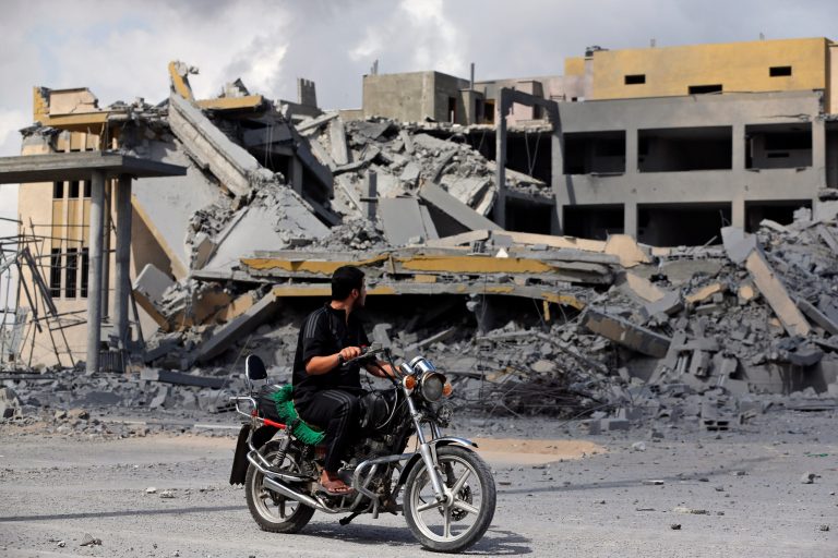 A Palestinian man rides past a transition center for newly released convicts that was empty and not yet operational, that was hit by an overnight Israeli missile strike in Rafah, southern Gaza Strip, Tuesday. (AP/Lefteris Pitarakis)