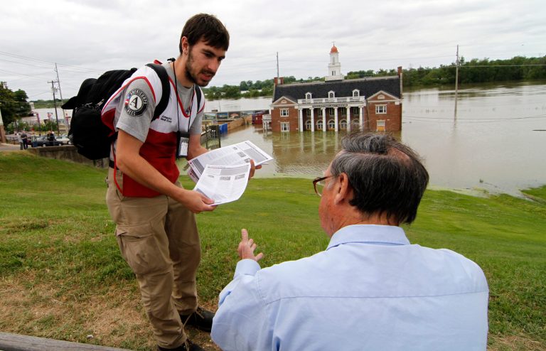 An AmeriCorps volunteer hands out Red Cross informational flyers on how to return to flooded homes, in Vicksburg, Miss., in May 2011. (AP Photo/Rogelio V. Solis)