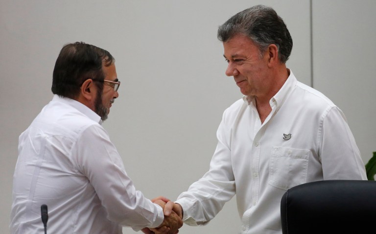 Colombian President Juan Manuel Santos, right, and commander of the Revolutionary Armed Forces of Colombia or FARC, Rodrigo Londono, shake hands after a signing ceremony marking a cease-fire and rebel disarmament deal, in Havana, Cuba in June. (AP Photo/Desmond Boylan)
