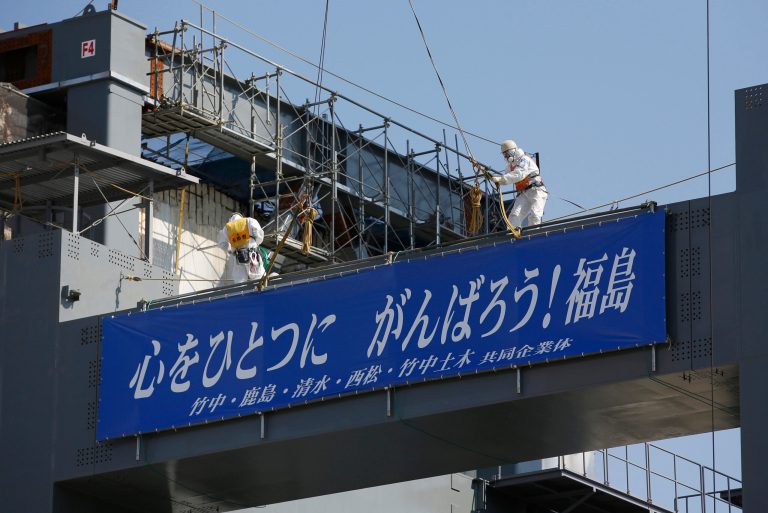 Workers wearing protective suits and masks build the foundation of a storage for melted fuel rods next to the Unit 4 reactor at Tokyo Electric Power Co.'s tsunami-crippled Fukushima Dai-ichi nuclear power plant in Okuma, Fukushima prefecture. (AP/Issei Kato)