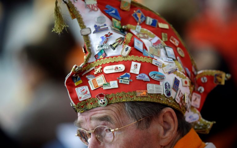 A Dutch skating fan, his hat filled with Olympic pins, watches the women's 1,000-meter speedskating race at the Adler Arena Skating Center during the 2014 Winter Olympics in Sochi, Russia, Thursday, Feb. 13, 2014. (AP Photo/David J. Phillip )