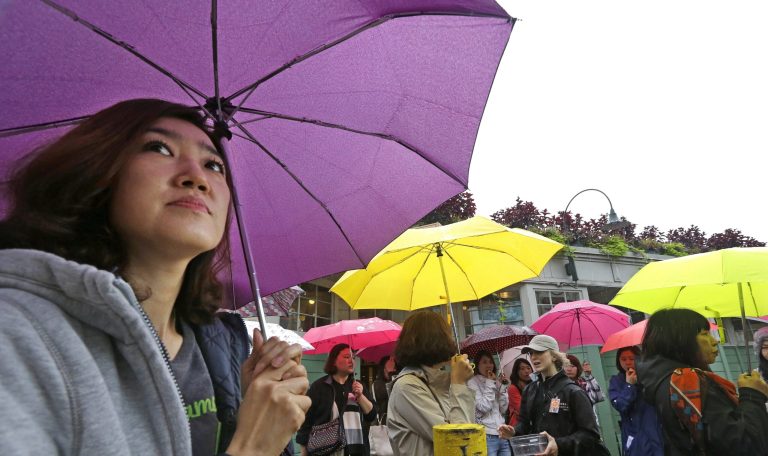 A group of tourists from Korea huddle under umbrellas as while touring the Pike Place Market in the rain Wednesday morning, Sept. 24, 2014, in Seattle. The first fall rainstorm in Western Washington kept gutters running overnight, slickened roads, revived lawns and reminded residents the warm, dry summer is over. In the 24 hours ending at 6 a.m. Wednesday, the National Weather Service reported 0.98 inch of rain at Sea-Tac Airport, 1.13 inches at Olympia and 0.60 at Everett. (AP Photo/Elaine Thompson)