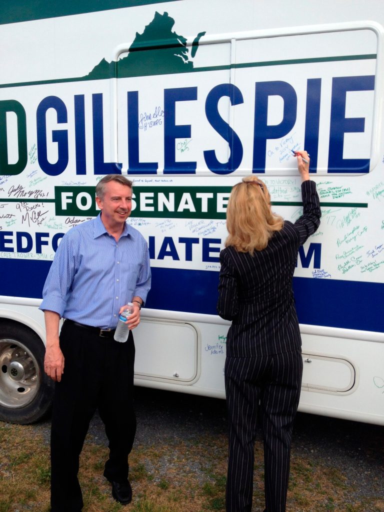 Virginia GOP Senate candidate Ed Gillespie watches as state Del. Barbara Comstock, running for a House seat, signs his campaign RV.