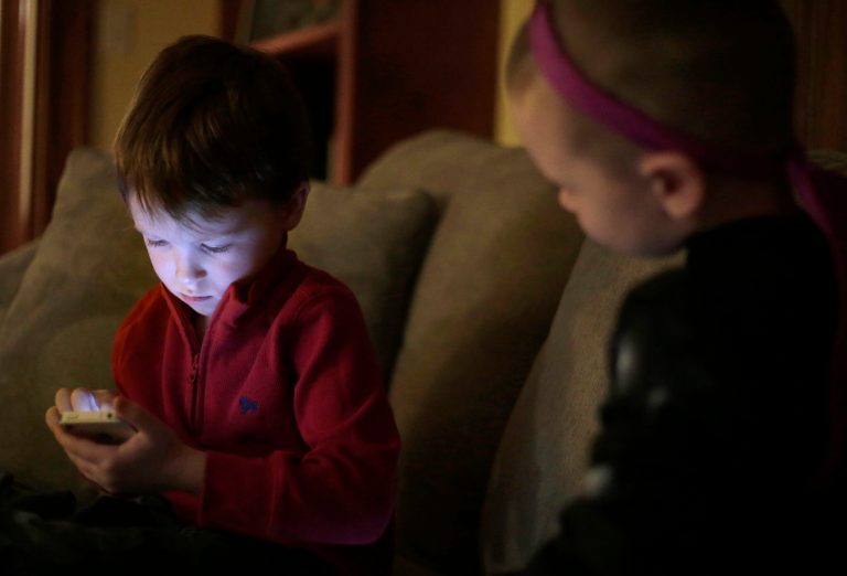 Jameson Young, 4, left, plays with a smart phone as his brother Nolan, 3, looks on at their home, in Boston, Monday, Jan. 27, 2014. Pew reports that parents are watching over the shoulders of their kids. (AP Photo/Steven Senne)