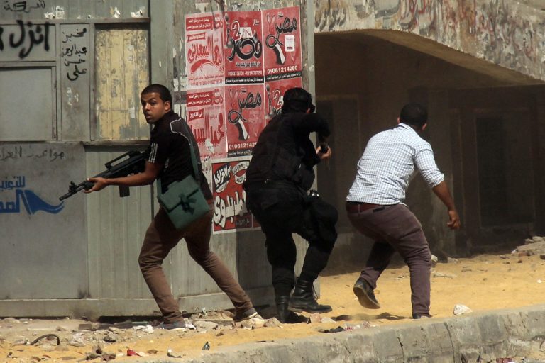 Members of the Egyptian security forces hold guns during clashes with supporters of the Muslim Brotherhood outside Al-Azhar University in Cairo, Egypt, Friday, May 23, 2014. Two protesters were killed in clashes in Egypt between Islamist demonstrators and their opponents after midday prayers Friday, the final day of campaigning ahead of next week's presidential election, authorities said. (AP Photo/Ahmed Taranh)