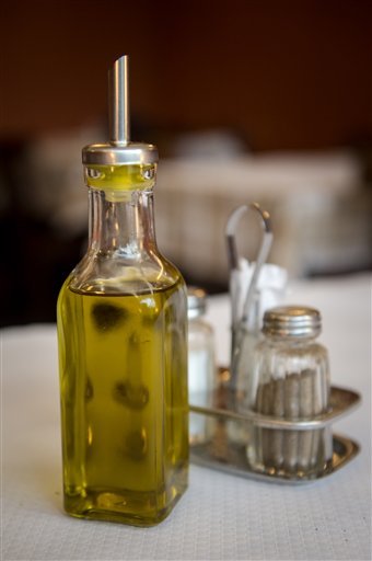 A refillable bottle of olive oil stands next to salt and pepper shakers in an Italian restaurant in Brussels, Friday, May 17, 2013. The European Union plans to ban the glass jar which is filled, and refilled, with golden olive oil from restaurant tables across the EU. Photo: Geert Vanden Wijngaert/AP)