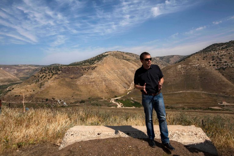 In this photo taken Wednesday, April 24, 2013, Gal Hirsch, a reserve Israeli General, stands at an army outpost overlooking Syria and Jordan in the Golan Heights. Against a breathtaking vista of green fields and a snowcapped mountain range, all is silent but for a strong gust of wind whipping across the landscape. The tranquility is suddenly interrupted by a burst of gunfire from beyond a newly built fortified fence: Jihadi rebels are battling with Bashar Assad's battered troops in a nearby Syrian village. Watching it all unfold are Israeli soldiers atop tanks - a sight unseen here in a generation - and the sounds of explosions from a large-scale Israeli drill are distinctly heard in the background. (AP Photo/Sebastian Scheiner)