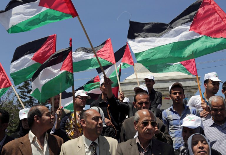 File - In this April 22, 2014 file photo, Palestinians wave their national flags during a rally to demand the end of Palestinian political divisions, at the main square of Gaza City. Propelled by crises, rivals Hamas and Fatah are moving toward forming a unity government by next week, in what appears to be their most promising attempt yet to end a seven-year rift that weakened the Palestinian case for statehood. (AP Photo/Adel Hana, File)
