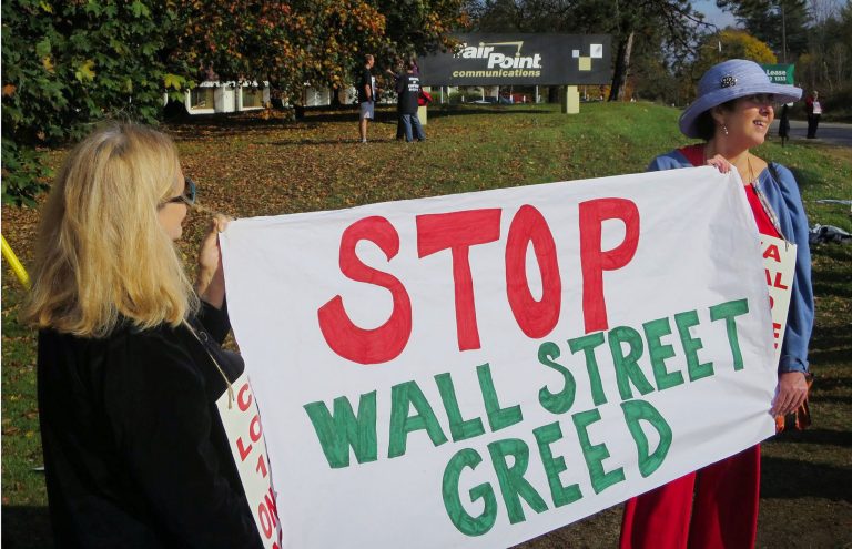 Striking FairPoint Communications workers Maureen Berry, left, of Saco, Maine, and Joan Tsotsones of Portland, Maine, hold a sign denouncing corporate greed as workers picket Friday, Oct. 17, 2014, outside a company operations center in Portland, Maine. More than 1,700 FairPoint Communications workers in Maine, New Hampshire and Vermont went on strike demanding that the company return to the bargaining table.(AP Photo/David Sharp)