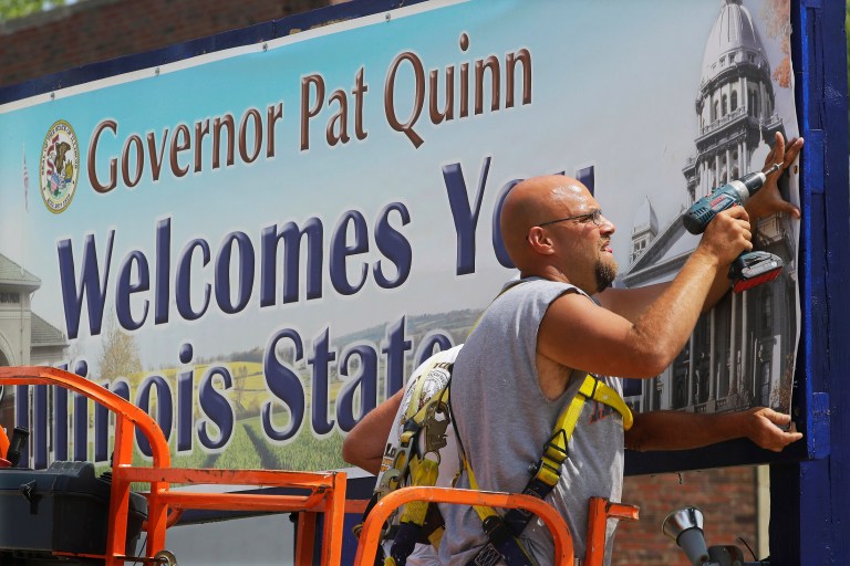 In this Wednesday, July 30, 2014 photo, Illinois Department of Agriculture contractor Don Davis helps put up a banner at the fairgrounds for the opening of the Illinois State Fair in Springfield, Ill. The annual agricultural extravaganza runs Aug. 7-17. (AP Photo/Seth Perlman)