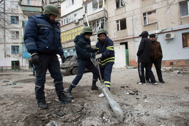 Rescue workers try to pull out a piece of an exploded Grad missile outside an apartment building in Vostochniy district of Mariupol, Eastern Ukraine, Sunday, Jan. 25, 2015. The Ukrainian president called the blitz a terrorist attack and NATO and the U.S. demanded that Russia stop supporting the rebels. (AP Photo/Evgeniy Maloletka)