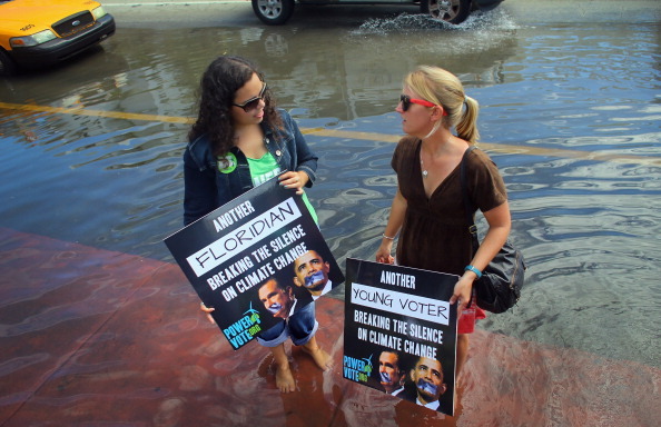 MIAMI BEACH, FL - OCTOBER 18: Jacquie Ayala (L) and Amanda Lawrence stand in a flooded street as they and others call on the presidential candidates to talk about their plans to fight climate change on October 18, 2012 in Miami Beach, Florida.  Some of the streets on Miami Beach are flooded due to unusually high tides that the protesters felt are due to rising seas, which are connected to global warming and climate change. Published reports indicate that Florida ranks as the most vulnerable state to sea-level rise, with some 2.4 million people, 1.3 million homes and 107 cities at risk from a four-foot rise in sea levels.  (Photo by Joe Raedle/Getty Images)
