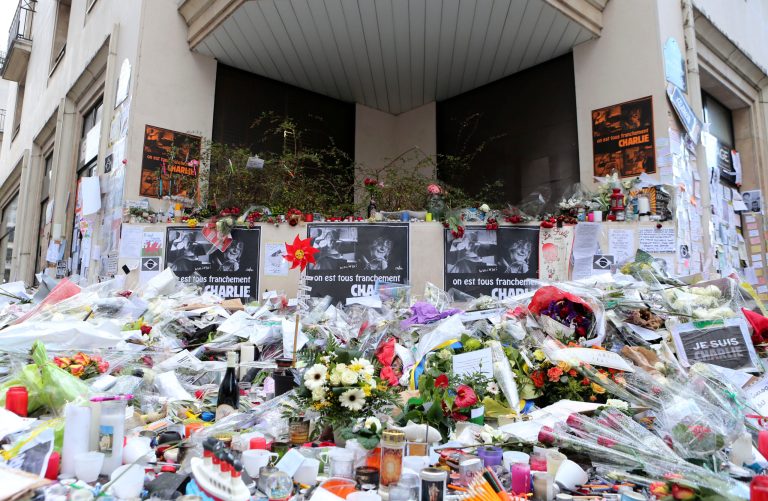 Flowers lay outside Charlie Hebdo headquarters in Paris, France, Wednesday, Jan. 14, 2015, one week after the attack on the newspaper. (AP Photo/Jacques Brinon)
