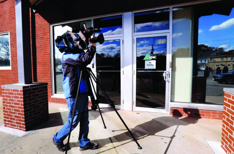 In this Thursday, Nov. 1, 2012, photo, a TV news photographer shoots the facade of the New England Compounding Center, which has since been linked to a recent deadly meningitis outbreak, in Framingham, Mass. According to a congressional investigation released Tuesday, Nov. 13, 2012, federal health inspectors wanted to shut down the New England Compounding Center, until it cleaned up its operations in 2002. Nearly 440 people have been sickened by contaminated steroid shots distributed by New England Compounding Center, and more than 32 deaths have been reported since the outbreak began in September, according to the Centers for Disease Control and Prevention. (AP Photo/Elise Amendola)