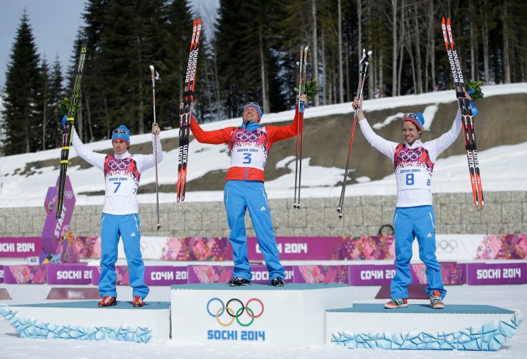 Russia's gold medal winner Alexander Legkov is flanked by Russia's silver medal winner Maxim Vylegzhanin, left and Russia's bronze medal winner Ilia Chernousov during the flower ceremony of the men's 50K cross-country race at the 2014 Winter Olympics, Sunday, Feb. 23, 2014, in Krasnaya Polyana, Russia. (AP Photo/Gregorio Borgia)