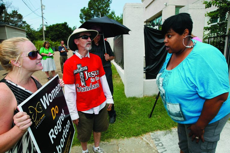FILE- In this Monday, July 2, 2012, file photo, abortion opponents Ron Nederhoed, center, and Ashley Sigrest, left, argue with Jackson Women's Health Organization's administrator Shannon Brewer, right, over the opponent's trespassing onto the property of Mississippi's only abortion clinic in Jackson, Miss. A federal judge on Friday July 13, 2012 allowed Mississippi's anti-abortion law to take effect but said the state's only clinic can remain open and will not face any penalties as it tries to comply with new requirements. (AP Photo/Rogelio V. Solis, File)