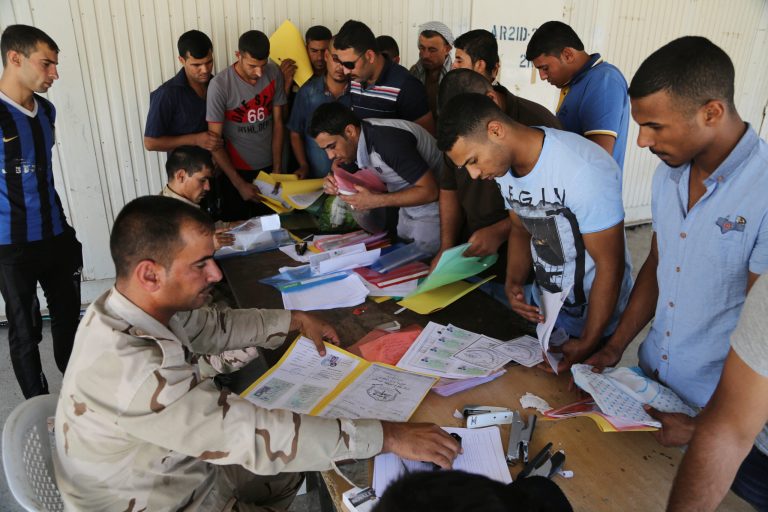 Iraqi men check in at the main army recruiting center as they volunteer for military services in Baghdad, Iraq, Wednesday, July 9, 2014, after authorities urged Iraqis to help battle insurgents. (AP Photo/Karim Kadim)