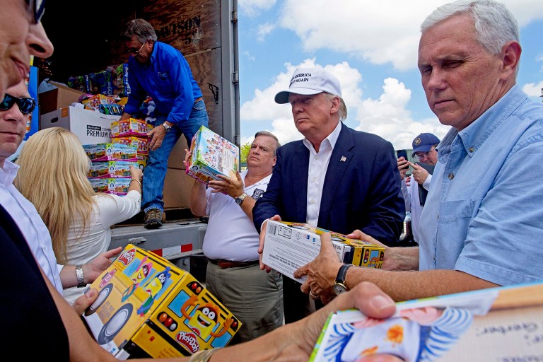 Republican presidential candidate Donald Trump and his running mate, Indiana Gov. Mike Pence, right, help to unload supplies for flood victims during a tour of the flood damaged area in Gonzales, La. (AP Photo/Max Becherer)