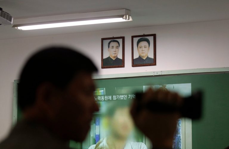 A visitor films exhibition near the pictures of North Korean founder late Kim Il Sung, left, and his son, leader late Kim Jong Il at the unification observation post near the border village of Panmunjom, that has separated the two Koreas since the Korean War, in Paju, north of Seoul, South Korea, Saturday, March 30, 2013. North Korea issued its latest belligerent threat Saturday, saying it has entered 
