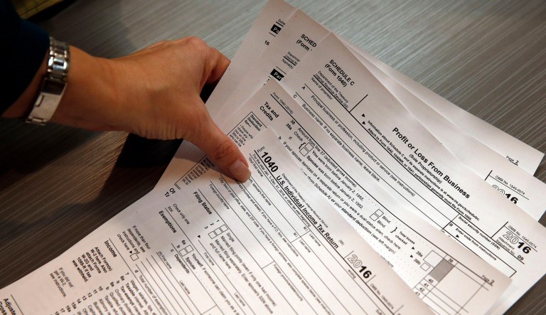 In this Jan. 14, 2017, file photo, tax preparation firm owner Alicia Utley reaches for hard copies of tax forms in her offices at Infinite Tax Solutions, in Boulder, Colo. (AP Photo/Brennan Linsley, File)