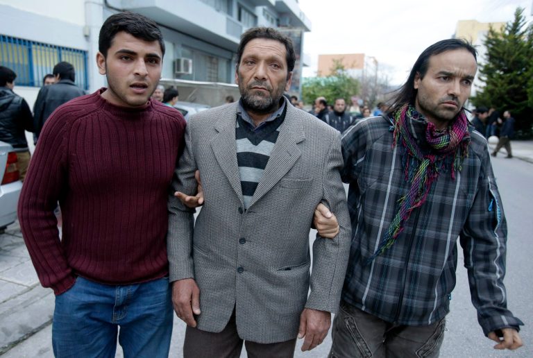 Afghan Fadi Mohamed, survivor of a boat which capsized, , center,  who lost his wife and three of his four children, is helped by his son, left, and a fellow countryman who lives in Greece after a prayer at a makeshift basement mosque in western Athens on Friday, Jan. 24, 2014. Twelve people, mostly children, are believed to have perished in Monday's sinking. Only two bodies have been found. Greece's merchant marine minister said Friday the survivors of a fatal migrant boat sinking changed their accounts of the incident, initially saying the Greek Coast Guard saved them but later accusing it of badly mishandling the rescue operation. (AP Photo/Thanassis Stavrakis)