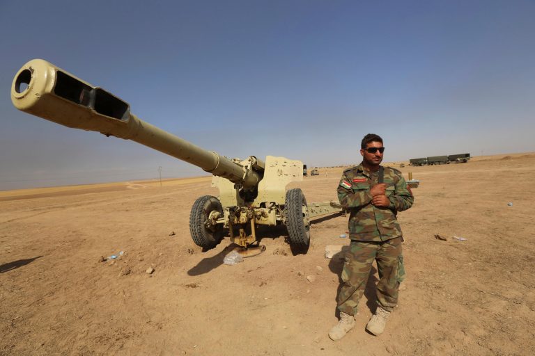 A Kurdish peshmerga fighter stands next to a firearm in Mahmoudiyah, Iraq, where fighters took control of it from the Islamic State group. (AP Photo/Hadi Mizban)
