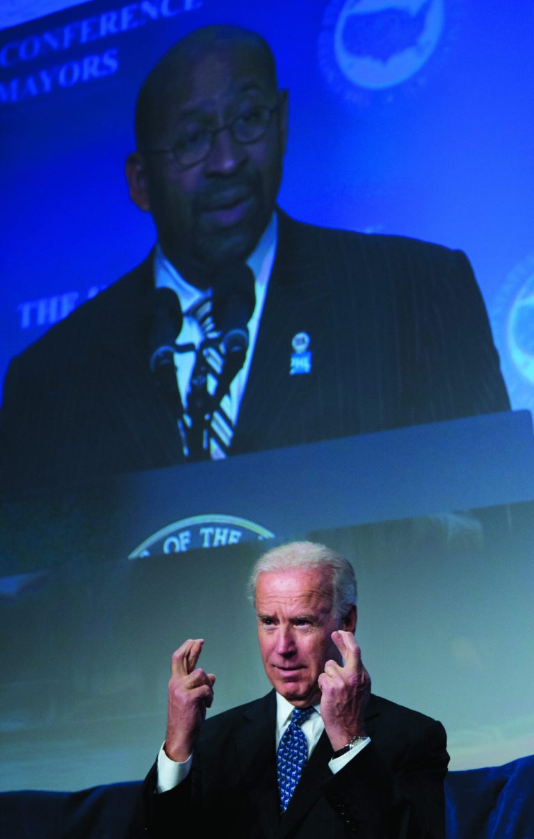 Vice President Joe Biden crosses his fingers as U.S. Conference of Mayors President, Philadelphia Mayor Michael Nutter projected on a monitor, makes his remarks at the U.S. Conference of Mayors 81st winter meeting in Washington, Thursday, Jan. 17, 2013. (AP Photo/Manuel Balce Ceneta)