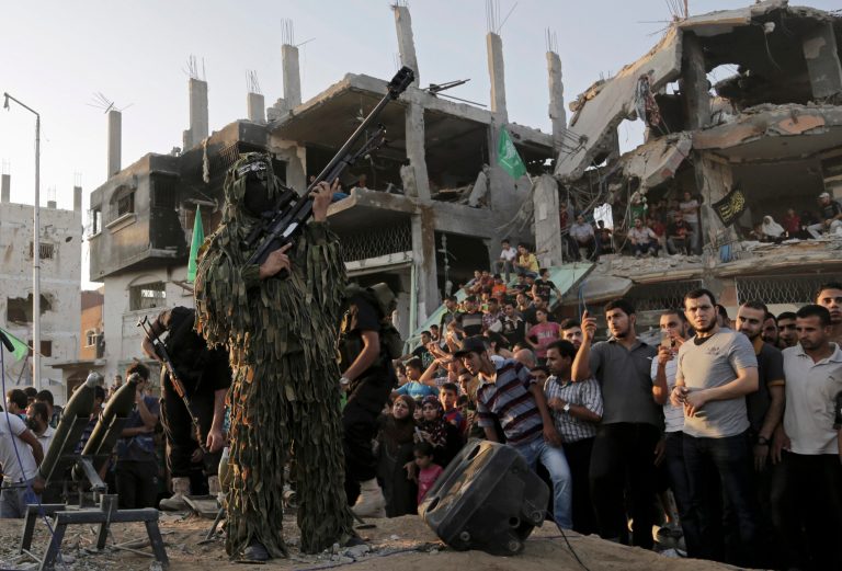 A Palestinian militant of Izzedine al-Qassam Brigades, military wing of Hamas, holds his rifle during a celebration of the victory rally at the debris of destroyed houses in Shijaiyah, neighborhood of Gaza City, in the northern Gaza Strip, Wednesday, Aug. 27, 2014. An open-ended cease-fire between Israel and Palestinian militants in the Gaza Strip was holding Wednesday. (AP Photo/Adel Hana)