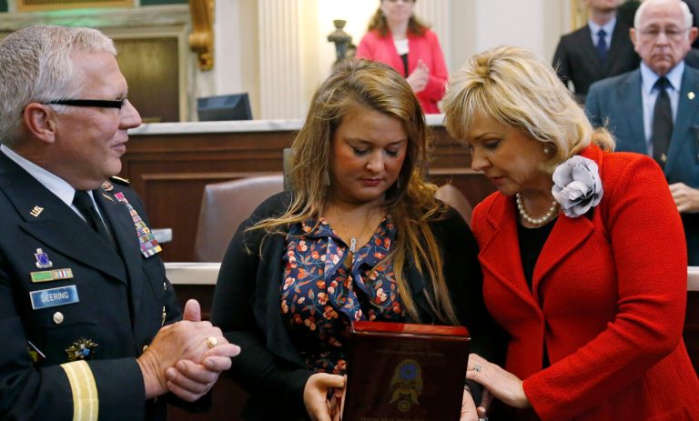 Major Gen. Myles L. Deering, left, adjutant general of the Oklahoma National Guard, looks on as Oklahoma Gov. Mary Fallin, right, and Jane Horton, center, the widow of Spc. Christopher Horton, look over the Oklahoma Gold Star Medal awarded to Horton on appreciation day for the Oklahoma National Guard's 45th Infantry Division, in the Oklahoma Legislature. The Gold Star Medal is an award created by the Legislature to honor Oklahoma military members killed in combat. (AP Photo/Sue Ogrocki, Pool)