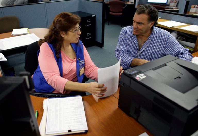 Rose Capote-Marcus, left, helps Waldemar Vega, 50, with problems he is having receiving his unemployment benefits at WorkForce One, in Davie, Fla. (AP/Lynne Sladky)