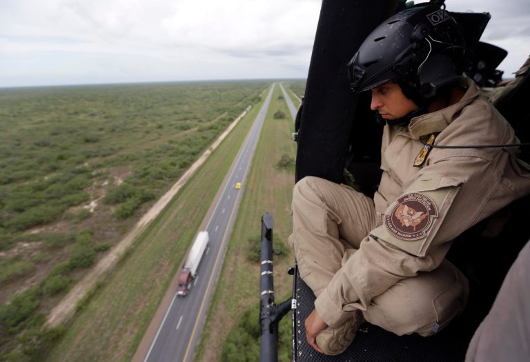 An U.S. Customs and Border Protection Air and Marine agent pears out of the open door of a helicopter during a patrol flight near the Texas-Mexico border near McAllen, Texas. (AP Photo/Eric Gay)